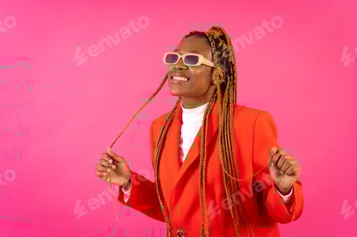 Preview: African young woman with braids a pink background, portrait in the studio in a red outfit having fun