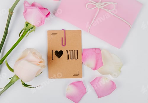 Preview: top view of white and pink color roses with envelope tied with a rope and small postcard