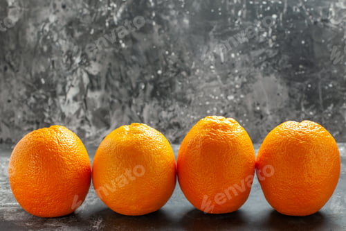 Preview: Front close view of three natural organic fresh oranges lined up in a row on dark background