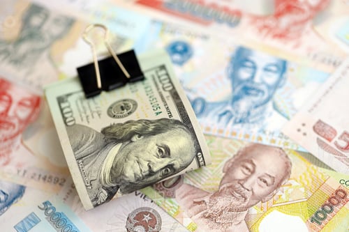 Preview: Vietnamese dong currency money bills and bunch of us dollar banknotes.