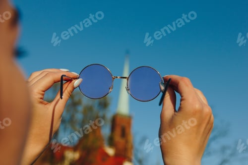 Preview: cropped shot of woman holding stylish sunglasses and looking through