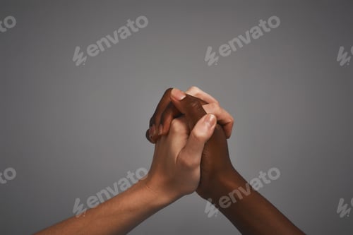 Preview: Studio shot of unidentifiable hands holding on to each other against a gray background
