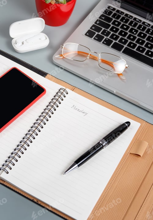 Preview: Laptop, cell phone and opened agenda on a grey desk close up.