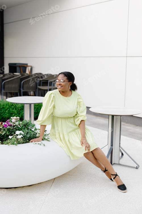 Preview: Dark-skinned lady laughs outside. Brunette woman in yellow dress smiles and walks outdoors