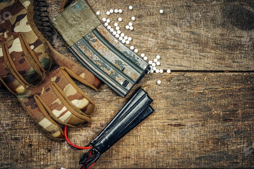 Preview: Close up of airsoft gun magazine and airsoft balls on wooden background