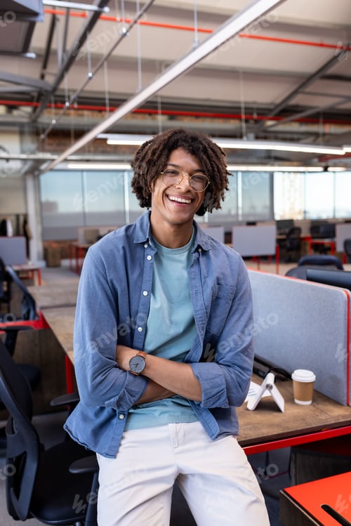 Preview: Smiling African American man in casual attire standing in modern office workspace