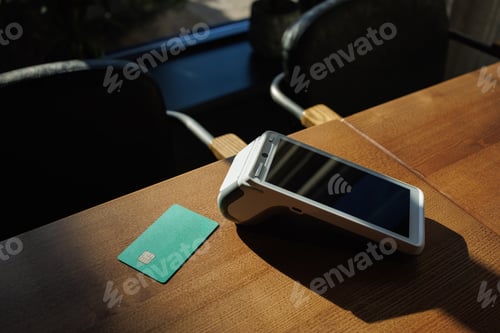 Preview: Close-up of payment terminal and credit card on table background. Credit card payment.