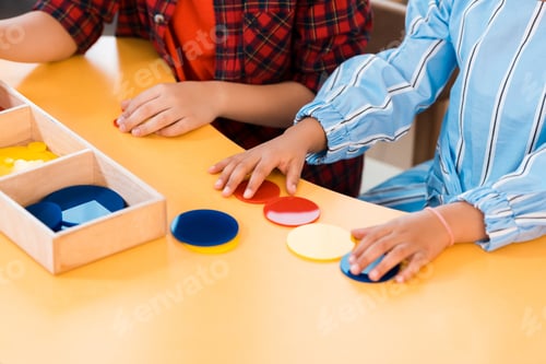 Preview: Cropped view of kids folding colorful game on table in montessori school