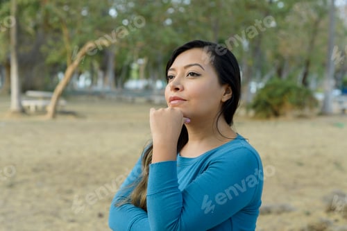 Preview: Woman in a public park with an attitude of preoccupation, pensive.