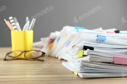 Preview: Stack of documents with binder clips and glasses on wooden table