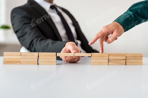 Preview: Businessman making a bridge of wooden blocks for his partner