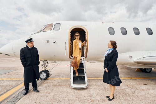 Preview: Landing is done. Airplane crew leads woman in yellow clothes from of a plane