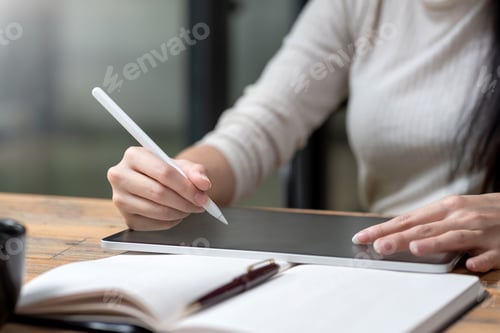 Preview: Close-up of a woman hand holding a stylus with a tablet at the office