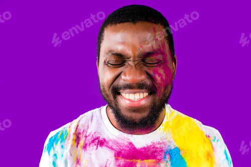 Preview: latin brazilian male in white cotton t-shirt with colorful paint of face laughing studio