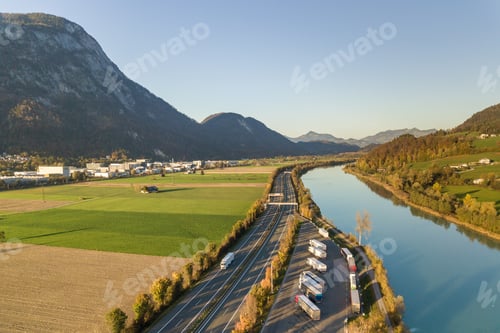 Preview: Aerial view of highway interstate road with fast moving traffic near big river in Alps mountains