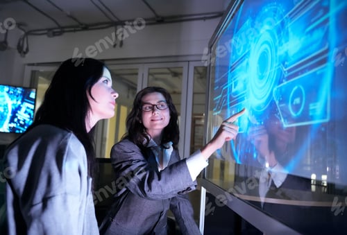 Preview: Business meeting on technology trends in modern office with digital display and two women