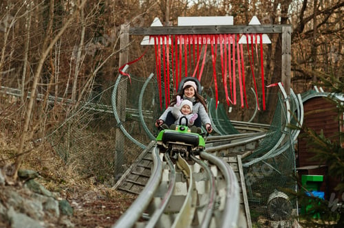 Preview: Mother with daughter ride electric sleigh on rails.
