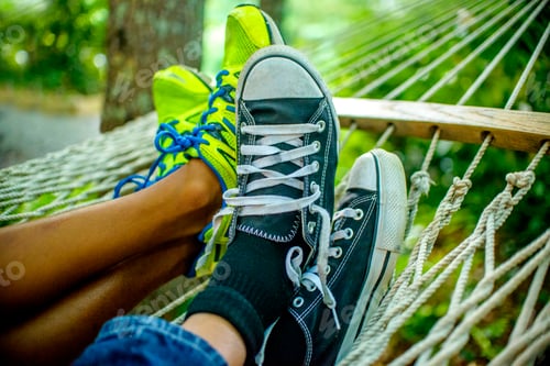 Preview: Legs of teenage boys lying in hammock