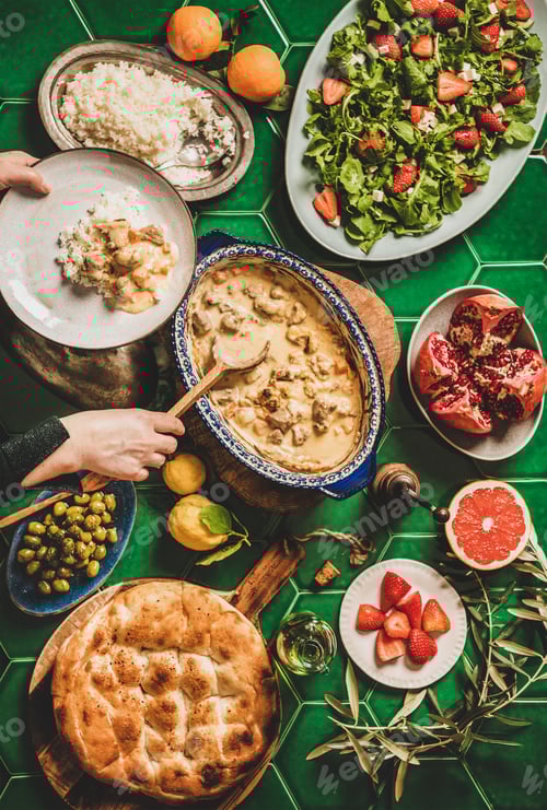 Preview: Female hands serving Turkish lamb in sauce over green table