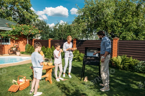 Preview: family having barbecue together on backyard on summer day