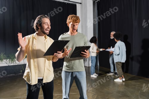 Preview: redhead and brunette students holding scenarios and rehearsing in acting skills school