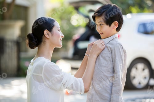 Preview: Young mother buttoning son's shirt