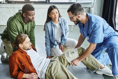 Preview: healthcare worker applying compressive bandage on leg of man near interracial participants during