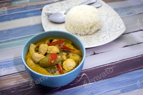 Preview: Green Curry With Fish Balls And Steamed Rice On A Wooden Table