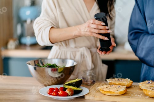 Preview: Close up of unrecognizable woman seasoning salad while preparing healthy breakfast in kitchen