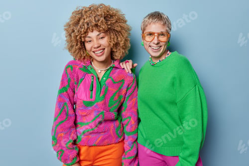 Preview: Photo of cheerful blonde European woman stand closely to each other in colorful clothes smile