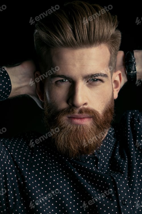 Preview: Handsome bearded man hipster with hands behind head looking at camera