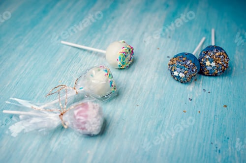 Preview: High angle shot of deliciously decorated pop cakes on a blue surface