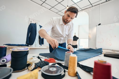 Preview: Man couturier measures length of large piece of fabric