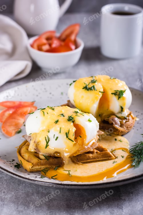 Preview: Eggs benedict and bacon on a crispy waffle on a plate for homemade breakfast. Vertical view