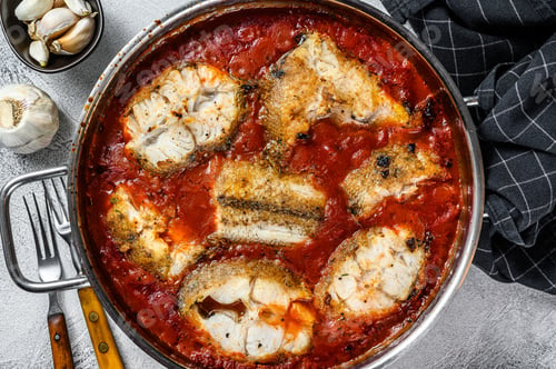 Preview: Baked grenadier macrurus white fish with tomato in a pan. White Wooden background. Top view