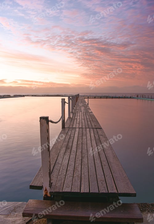 Preview: A beautiful sky at dawn, pink clouds above a timber jetty, peaceful tranquil morning