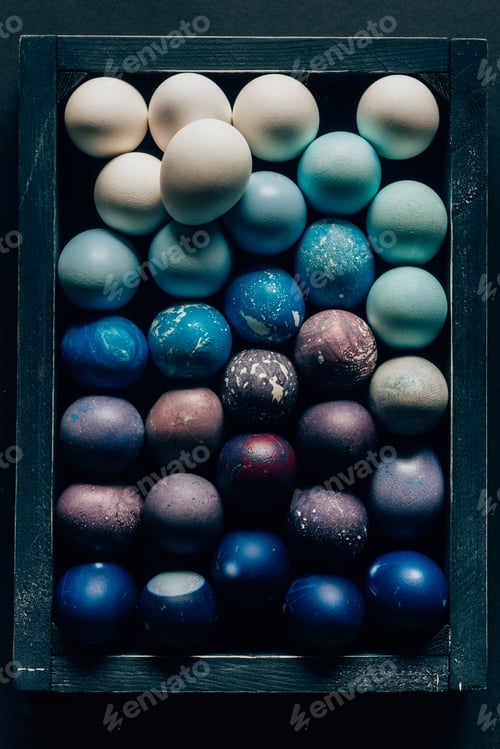 Preview: top view of colored painted easter eggs in wooden box on dark surface