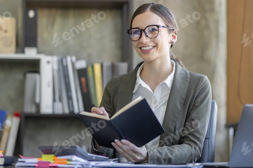 Preview: Portrait of smiling pretty young business woman in wearing glasses sitting on her workplace office,