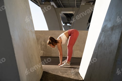 Preview: Slim sportswoman stretching muscles, makes functional training, slope before workout and jogging.