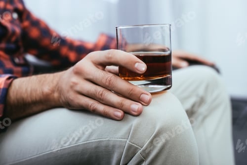 Preview: cropped shot of young man holding glass of whiskey