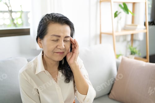Preview: Middle age Asian woman touching forehead having headache suffering from
migraine. mature asian