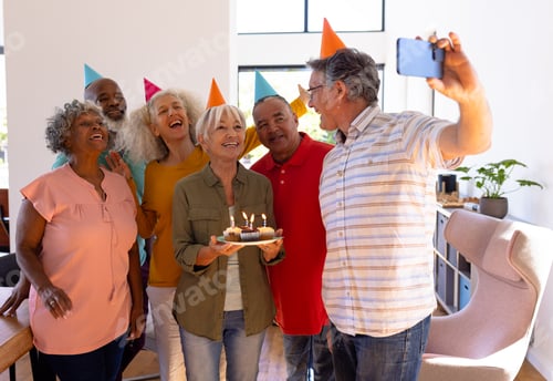 Preview: Senior man taking selfie with multiracial friends while enjoying birthday party in nursing home