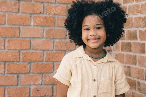 Preview: cute black African healthy child girl standing happy smile with copy space brick wall in school.
