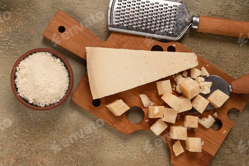 Preview: Freshly sliced and grated cheese, parmesan cheese, on a wooden chopping board, rustic style,
