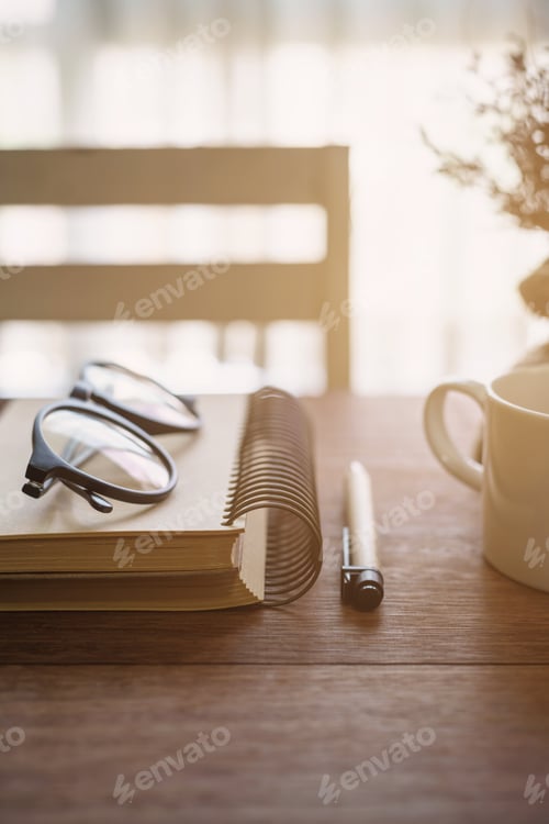Preview: Notebook and cup of coffee with sunlight on desk office