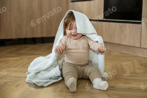 Preview: Portrait of a cute little girl sitting on the floor and playing with her blanket.