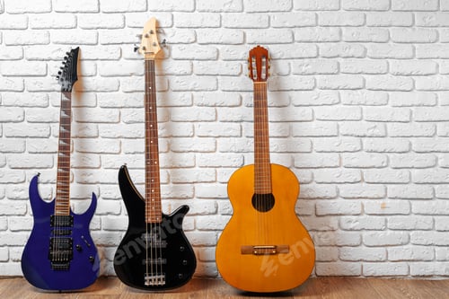 Preview: Set of guitars on the floor against white brick wall