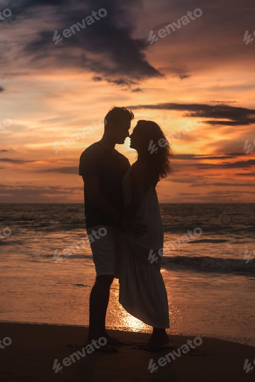Preview: Silhouettes of couple in love togetherness posing at tropical sea sunset, full body