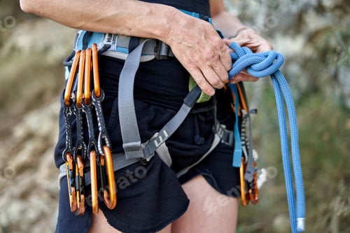 Preview: woman equipped with a climbing harness holds onto a rope