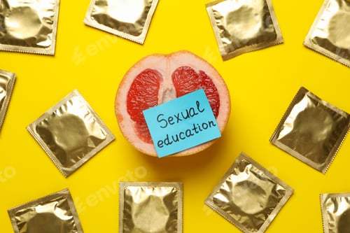 Preview: Pomelo with text Sexual education and condoms on yellow background